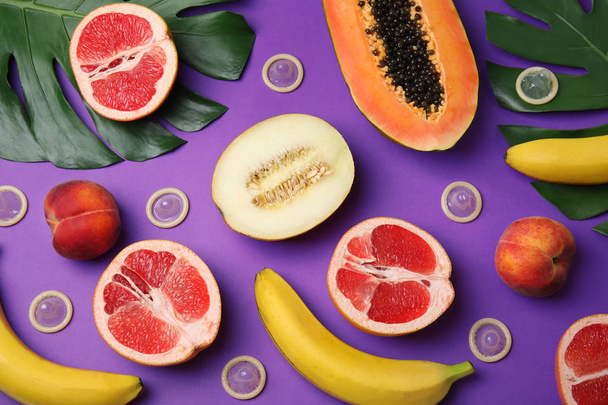 Flat lay composition with condoms and exotic fruits on purple background. Erotic concept - Photo, image
