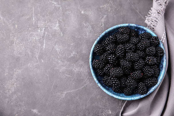 Bowl of ripe blackberries and fabric on grey table, flat lay with space for text - Foto, immagini