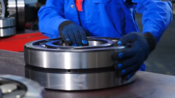Machinery and industry concept. Set of various gears and ball large bearings, spare parts warehouse. Male worker hands in blue uniform in bearing factory. Mechanic assembles bearings. A qualified - Footage, Video