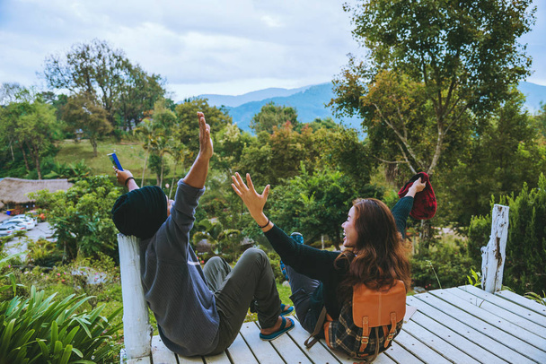 Paar liebt Naturreisen auf dem Berg, sitzt gemütlich beim Lesen von Büchern inmitten der Natur auf der weißen Holzbrücke. - Foto, Bild