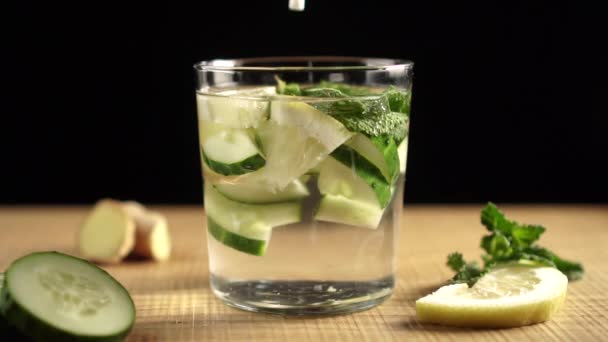 Stir the white plastic straw of the Sassi cocktail ingredients in a glass. Water, lemon, cucumber, imbar, mint. Preparation of cleansing water Sassi for weight loss. - Footage, Video