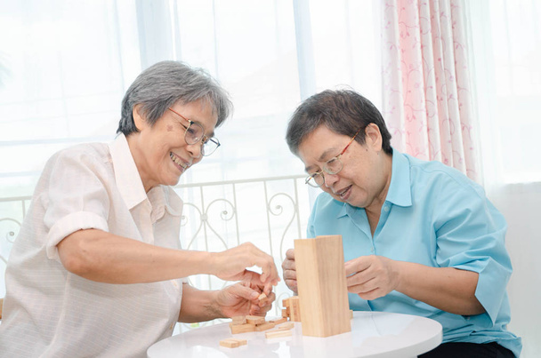 asiatische ältere Frauen in einem blauen Hemd und Freundin spielen Spiele haben Spaß am Morgen zu Hause im Zimmer. - Foto, Bild