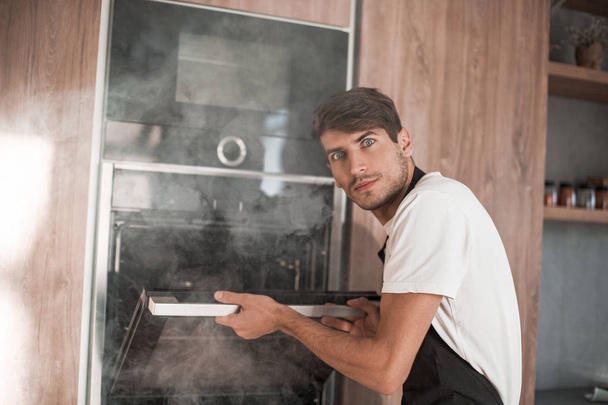 frustrated young man standing near broken oven - 写真・画像