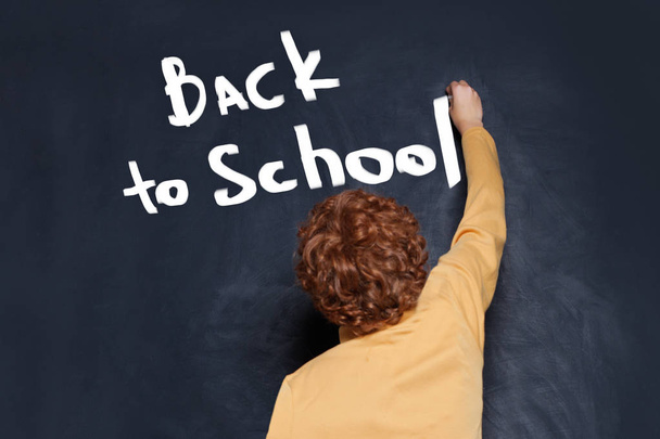 Child writing boy Back to school text on chalkboard background - Photo, Image
