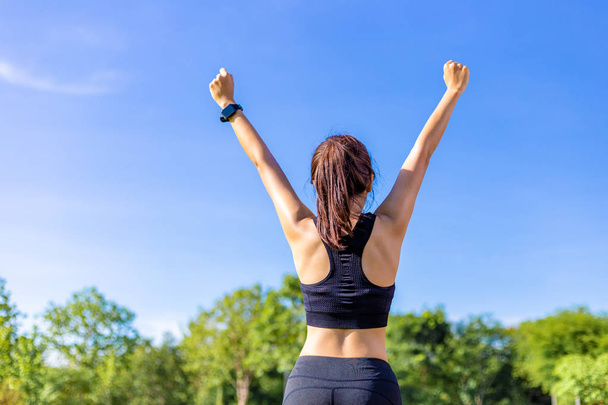 Happy young Asian woman raising up her arms cheerfully after com - Photo, Image