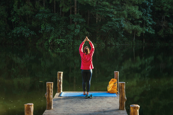 Las mujeres asiáticas se relajan en las vacaciones. Juega si es yoga. En el Moutain, Ejercicio, Jugar si el yoga en el puente de bambú al lado del lago en la niebla en Pang Ung, Tailandia
. - Foto, imagen