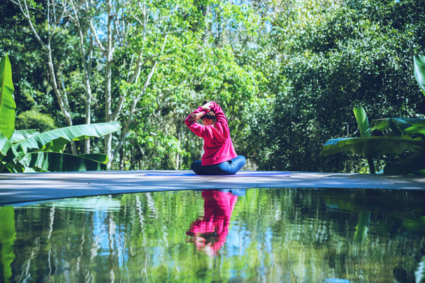 Jeune femme Voyage nature elle debout exercice à la piscine détente, Réflexions de femme asiatique sur la surface de l'eau
. - Photo, image