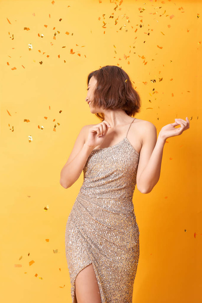 beautiful sexy woman in evening dress celebrating, golden confetti, party, smiling, inviting, happy - Фото, изображение