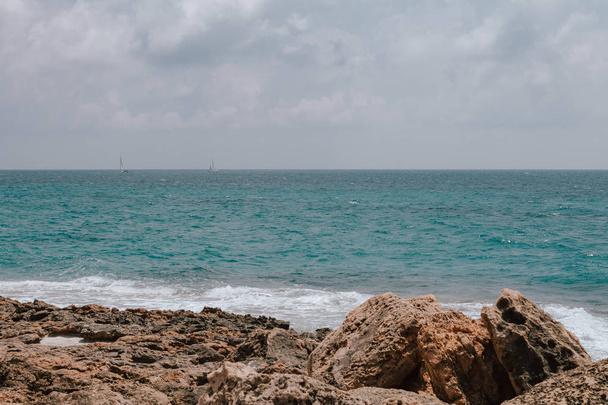 Felsstrand auf Mallorca, im Sommer bei Flut mit Wellen, die auf die Küste schlagen und brechen. - Foto, Bild