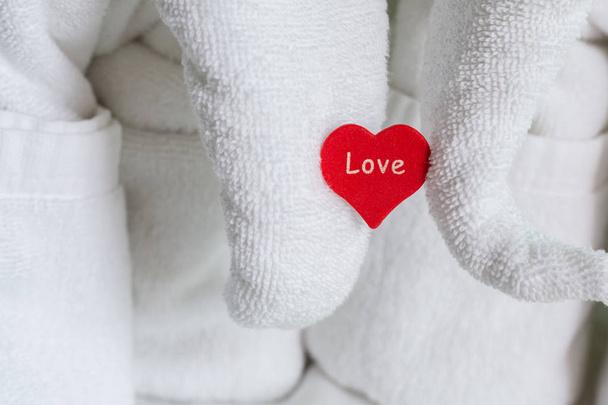 drewniane czerwone serce trzyma figurkę słoń białego ręcznik symbol kompozycji miłosnych pozdrowienia nowożeńcy w hotelu - Zdjęcie, obraz