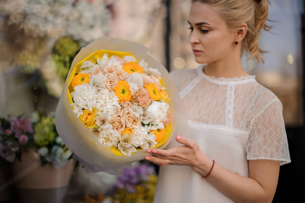 Dziewczyna trzyma Bukiet białych i żółtych kwiatów - Zdjęcie, obraz