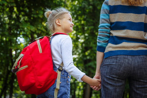 First day at school. Woman and girl with red backpack behind the back. Beginning of lessons. First day of fall. Back to school concept. - Fotografie, Obrázek