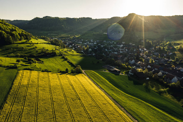 vista aérea del campo durante la hora dorada con flores amarillas en un pequeño pueblo, campo de colza en plena flor, primavera en el campo Suiza
 - Foto, imagen