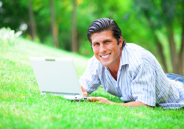 緑の芝生でノートパソコンを持つ学生 - 写真・画像