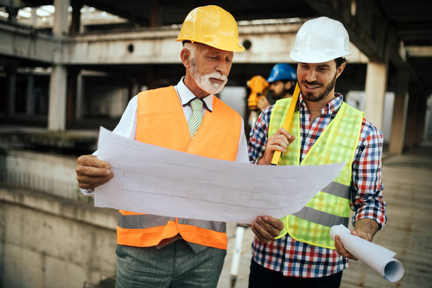 Engineer and construction site manager working with blueprints and plans - Valokuva, kuva