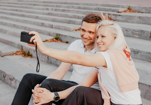 Young happy couple in love making selfie on retro camera on city street - Φωτογραφία, εικόνα