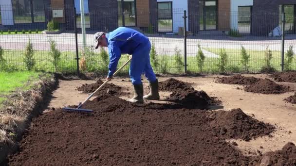 İş giyim erkek peyzajında çim tohumlama için zemin toprak hazırlamak. Statik çekim - Video, Çekim