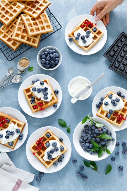 Traditional belgian waffles with cream cheese and fresh blueberry on blue background, top view - Zdjęcie, obraz