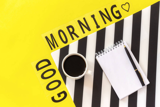 Text Good morning, coffee, notebook for text on stylish black and white napkin on yellow background. Concept good morning - Фото, изображение