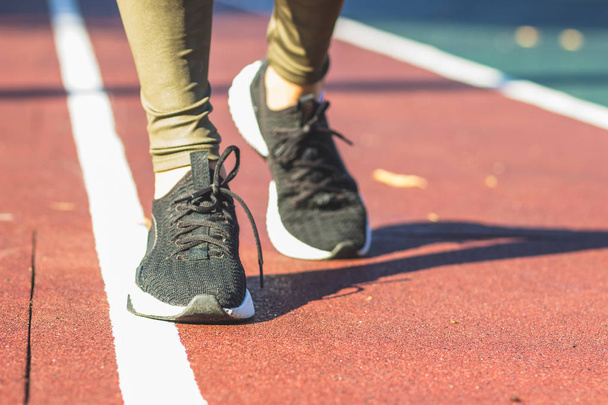 Mujer en zapatillas y ropa deportiva hace ejercicios deportivos en el campo de atletismo, fondo borroso
 - Foto, imagen