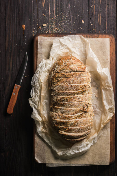 Szeletelt cipó a kenyérsütés papíron kés mellett - Fotó, kép