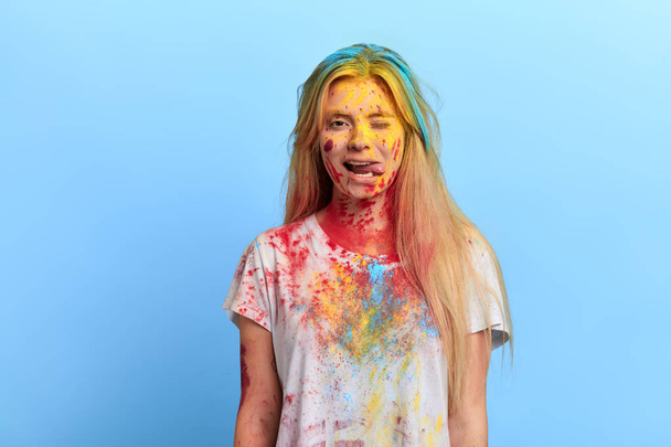 girl with dirty clothes and face linking her tongue and winkingat the camera - Photo, image