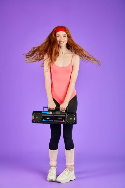 feliz estudiante chica con largo rizado rojo baile de pelo con portátil retro cassette jugador
 - Foto, Imagen