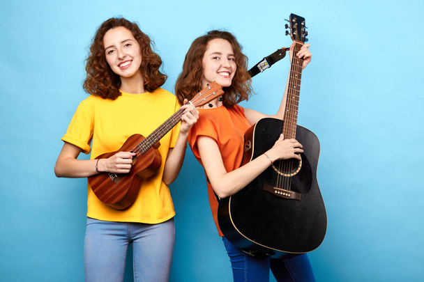 talented charming women enjoying playing the guitar - Foto, Imagen