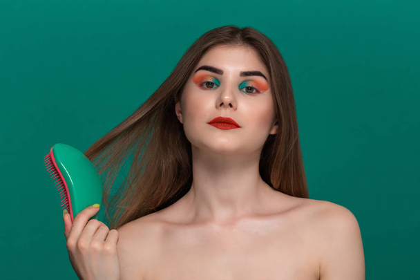 Retrato de bela jovem com cabelo penteado de maquiagem de cor brilhante com uma escova verde
 - Foto, Imagem