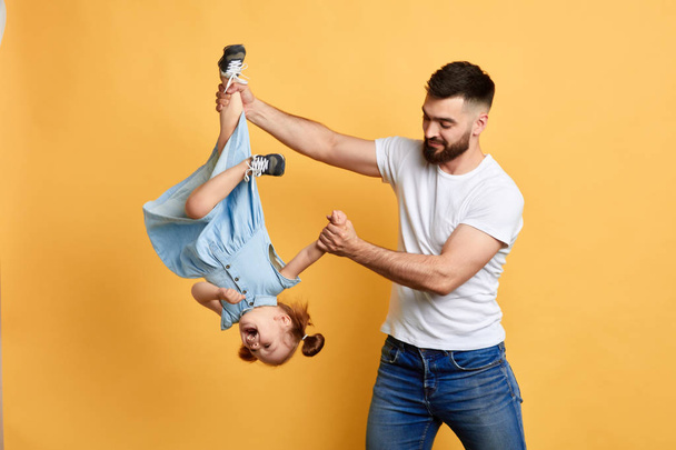 happy father playing with his adorable daughter, holding her upside down - Zdjęcie, obraz