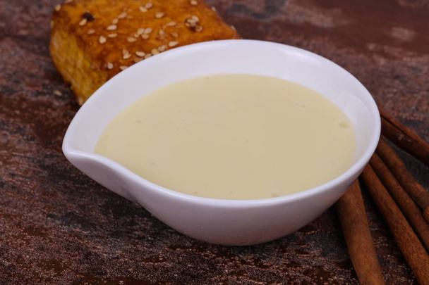 Condenced milk in the bowl with sinnamon and pastry - Photo, Image