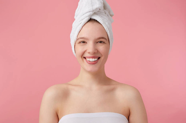 Κοντινό αποτέλεσμα της θετικής νεαρής κυρίας μετά το ντους με μια πετσέτα πάνω της - Φωτογραφία, εικόνα