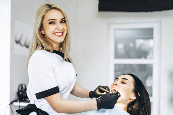 Pretty young female dentist making examination and treatment for - Photo, image