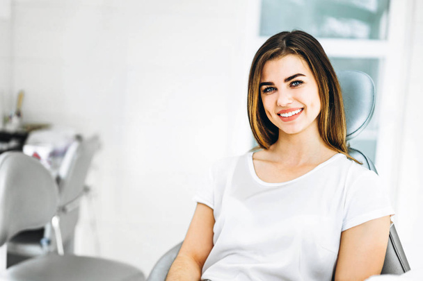 Pretty happy and smiling dental patient sitting in the dental ch - 写真・画像