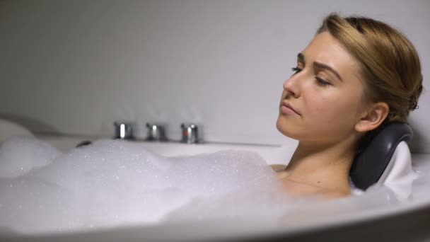 Upset woman lying in bath with foam bubbles, relieving stress, life problems - Materiał filmowy, wideo