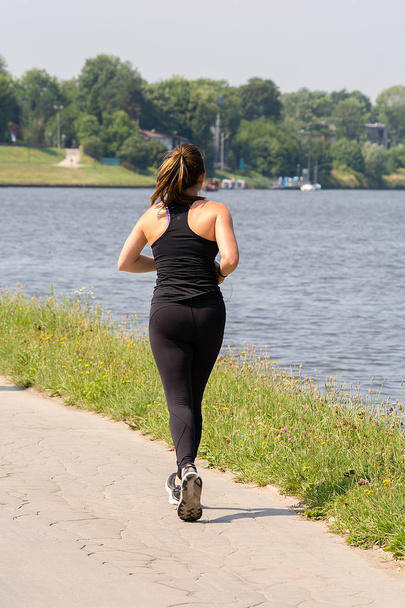 Mujer joven corriendo cerca del río en un día soleado
 - Foto, imagen