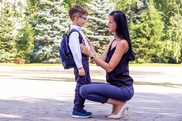 junge brünette Mutter eskortiert ihren Erstklässler Sohn zur Schule - Foto, Bild