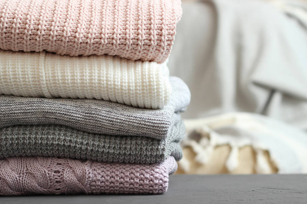A pile of warm sweaters on a wooden table on a color background. Autumn and winter clothes. - Foto, immagini