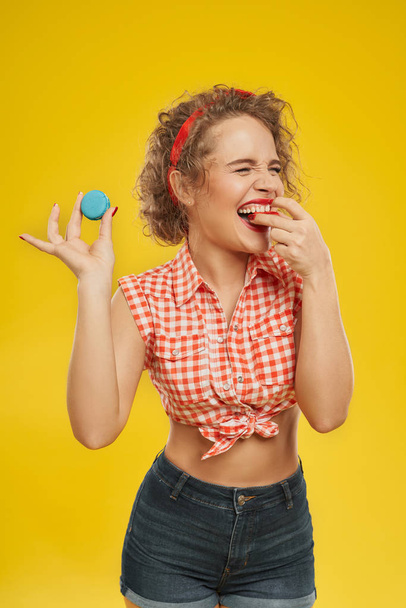 Beautiful girl with red lips bitting delicious red macaron. - 写真・画像