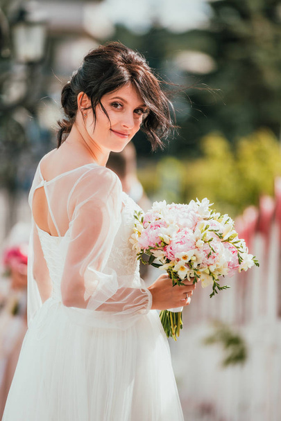 Wedding. Young beautiful bride posing in white dress and veil. Ease, real emotions. Soft light summer portrait. Girl looking at camera - Foto, Bild