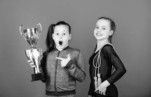 Deserved award. Girls athletic kids celebrate victory. Athletic girls with golden goblet. Win championship. Our team first place. Children gymnasts athletic kids happy champions. Sport achievement - Foto, afbeelding