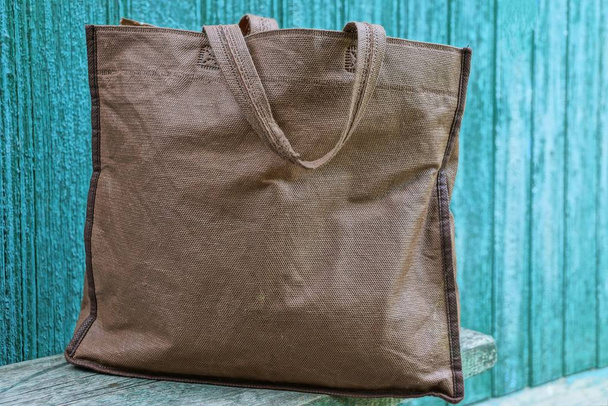 a large brown cloth bag is on a wooden table against a green wall - Foto, Imagem