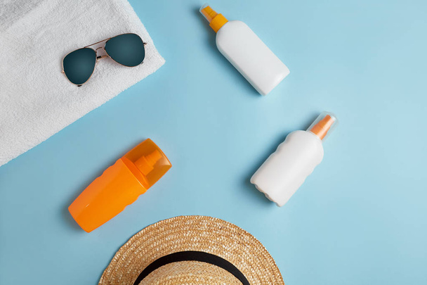 Sunscreen bottle,  sun hat, cream, lotion bottle, various sunscreens and seashells on a blue background. summer. vacation. Sun protection. top view - Φωτογραφία, εικόνα
