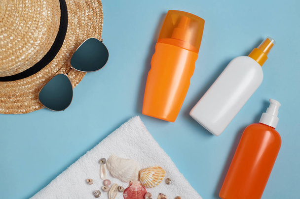 Sun cream, sun hat, cream, sunscreen bottle, sun cream, lotion bottle, seashells on a blue background. Sun protection. Beach flat lay accessories. Summer travel holiday concept. Summertime vacation - Φωτογραφία, εικόνα