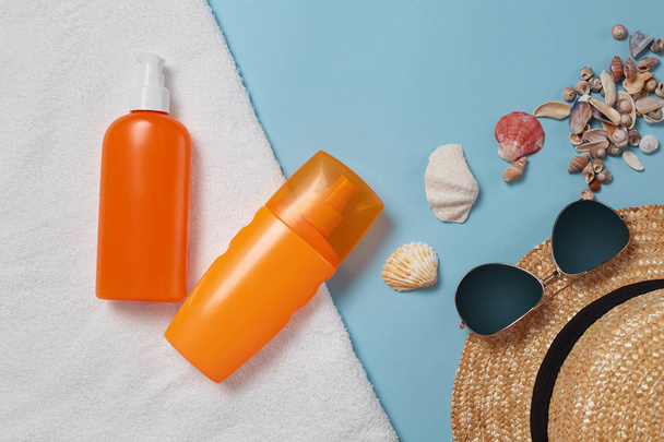Sunscreen bottle,  sun hat, cream, lotion bottle, various sunscreens and seashells on a blue background. summer. vacation. Sun protection. top view - Foto, imagen