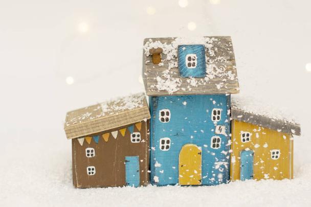 Scandinavian Christmas cozy toy houses made of natural wood handmade on a white snow-covered background. Minimalism. - Foto, Imagen