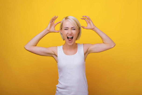 Портрет розлюченої молодої жінки, що кричить на жовтому тлі
 - Фото, зображення