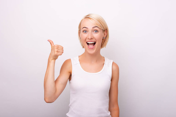 Portrait of beautiful amazed woman showing thumbs up gesture ove - Photo, Image