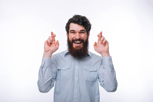 Портрет улыбающегося мужчины со скрещенными пальцами, стоящего над белым
 - Фото, изображение