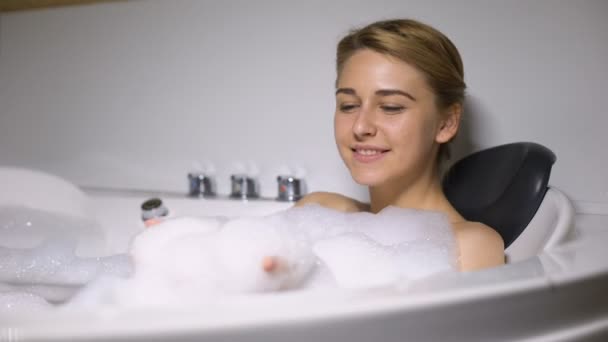 Funny female lying in bath, blowing foam bubbles into camera, childish mood - Footage, Video